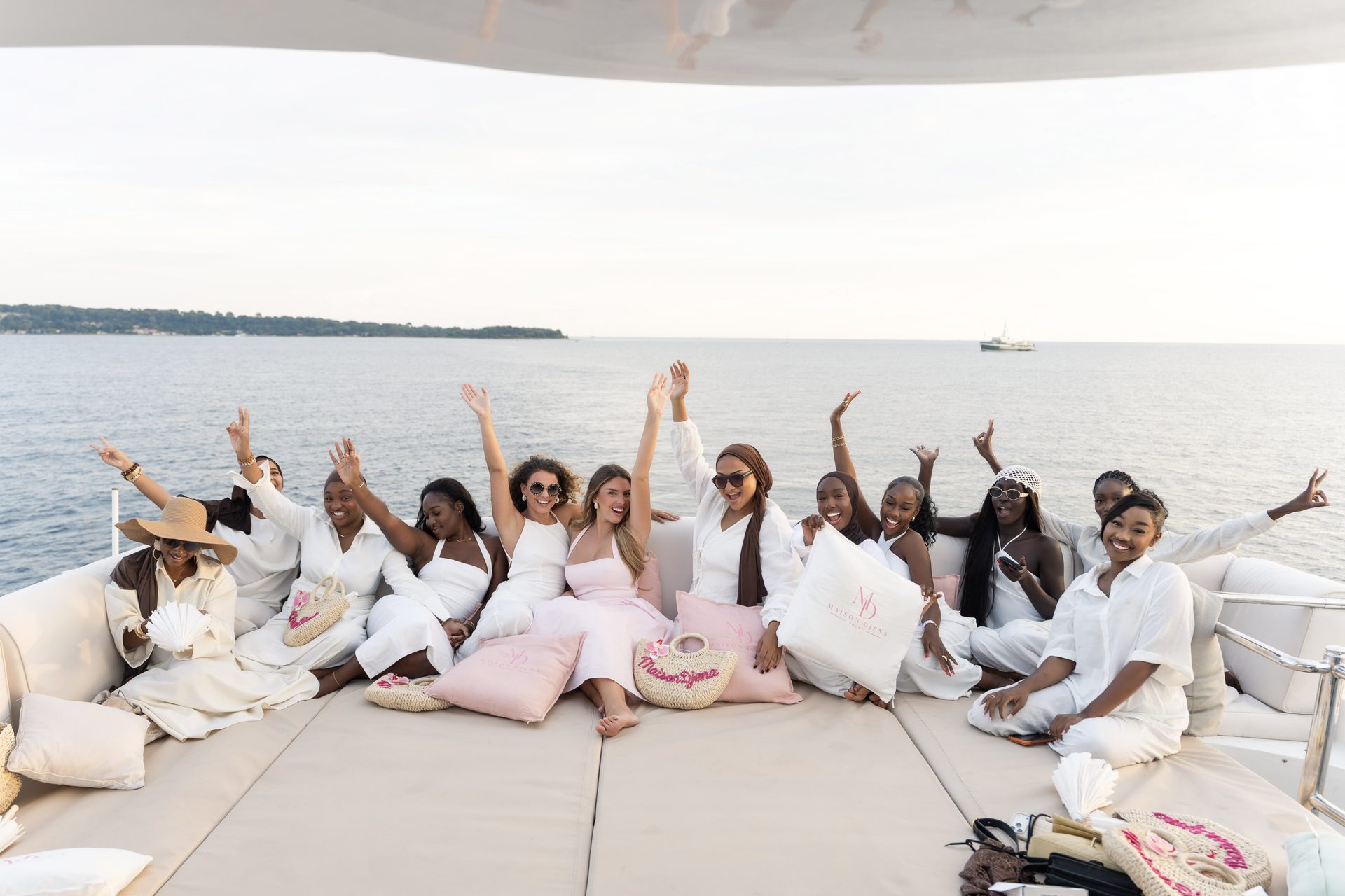 Le groupe de Djena en blanc, bras levés, sur le pont d'un yacht face à la mer